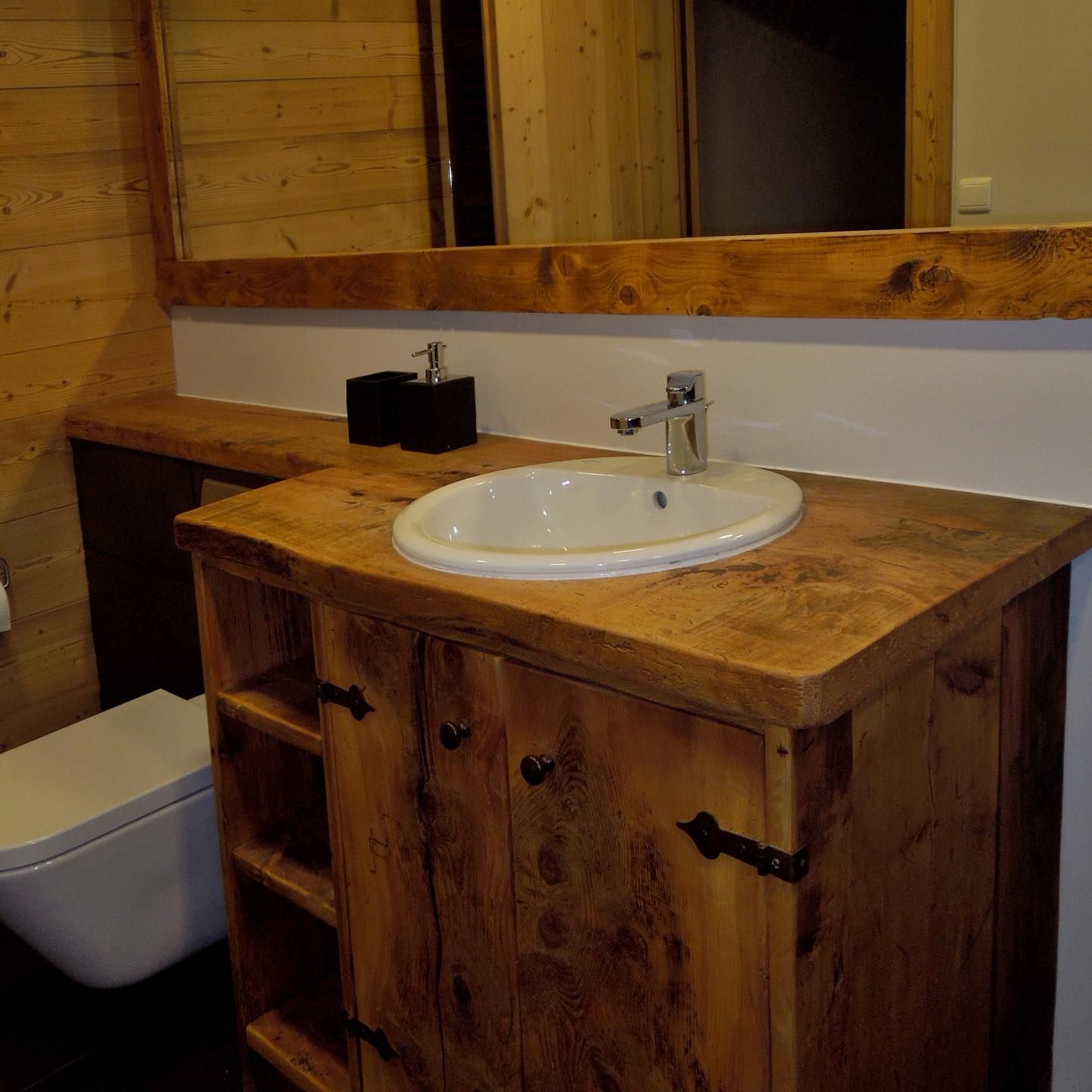 A small sink inserted into a thick slab of reclaimed wood.